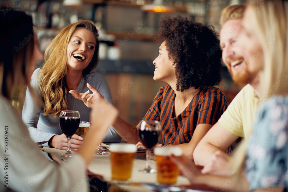 Friends chatting and drinking alcohol while sitting at restaurant. Multi ethnic group. Friends chatting and drinking alcohol while sitting at restaurant. Multi ethnic group.