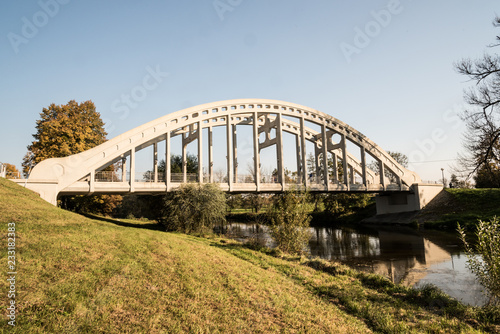 white concrete bridge over Olse river with colorful tree on the background and clear sky in Karvina city in Czech republic © honza28683