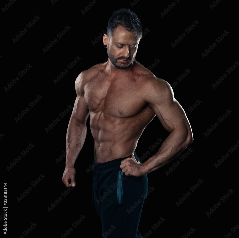 Fototapeta premium Brutal strong bodybuilder athletic man posing on black background.