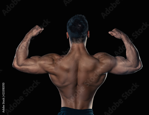 Brutal strong bodybuilder athletic man posing on black background.