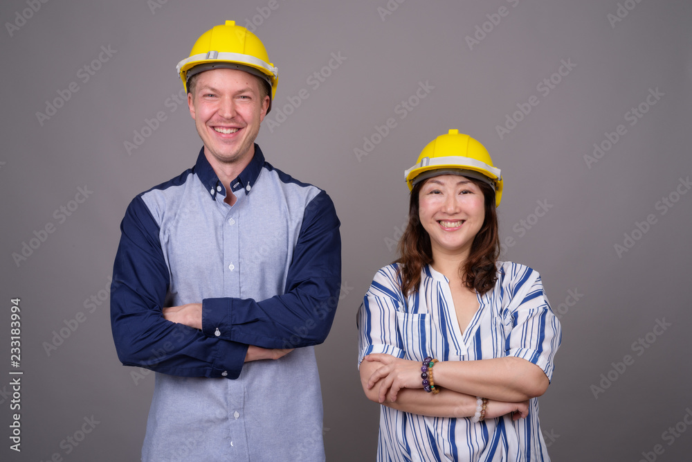 Businessman and mature Asian businesswoman wearing hardhat Businessman and mature Asian businesswoman wearing hardhat