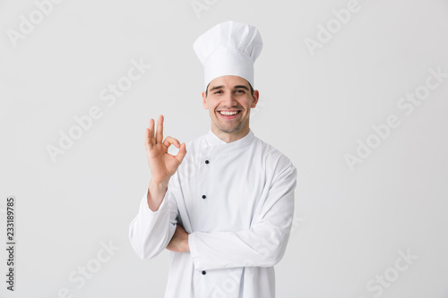 Handsome young man chef indoors isolated over white wall background. photo