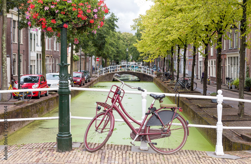 Delft city view in the Netherlands with water canal and vintage bicycle on the bridge in summer