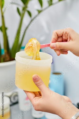 The girl is stirring pasta for sugaring in a jar. Hair Epilation photo