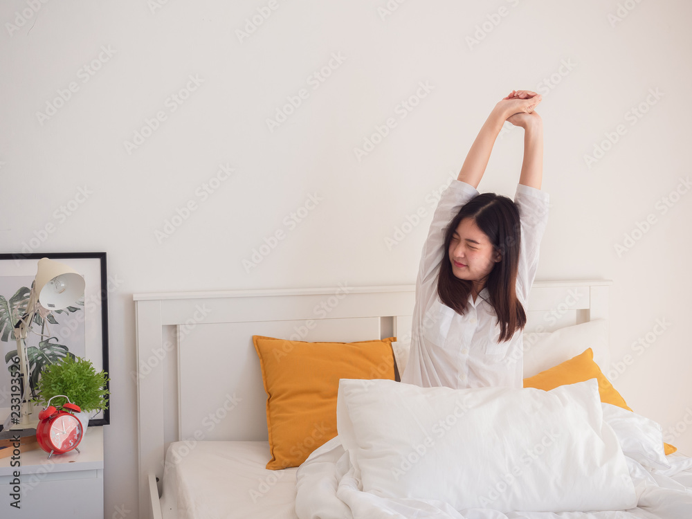 asian woman stretching in bed after wake up asian woman stretching in bed after wake up