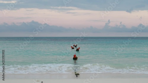 Buoys swinging on the waves with the Ocean View in Early morning on the beach with the pier in Holguin province of Cuba in October 2018 photo