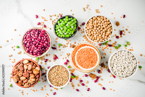 Various assortment of legumes - beans, soy beans, chickpeas, lentils, green peas. Healthy eating concept. Vegetable proteins. White marble background copy space top view photo