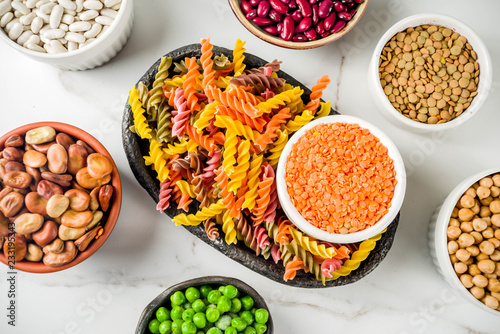Trend healthy food, vegan diet concept. Multi colored legume pasta with raw beans. Beans, chickpeas, green peas, lentils. Copy space top view
