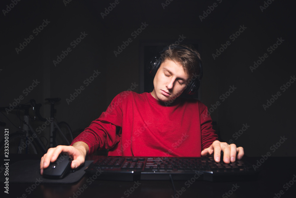 Teen gamer sleeps at home while playing video games. Young man uses a computer and sleeps. Gamer concept Sleeping during the video game