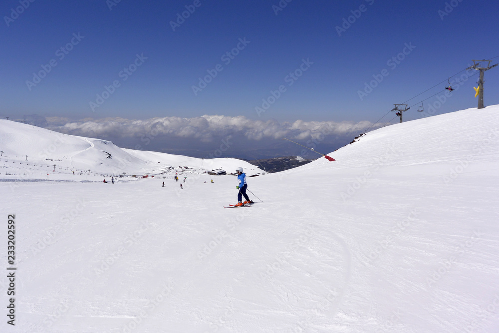 A boy in a blue  ski jumpsuit skiing from the snowy mountains of the Sierra Nevada