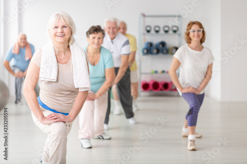Smiling senior woman with towel exercising during fitness classes for elderly people