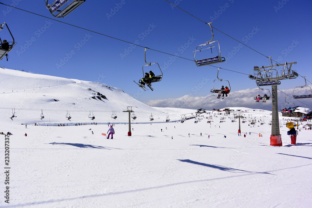 Skiers are going up on  the mountain lifts on the snow-capped mountains of the Sierra Nevada