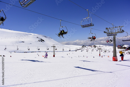 Skiers are going up on the mountain lifts on the snow-capped mountains of the Sierra Nevada