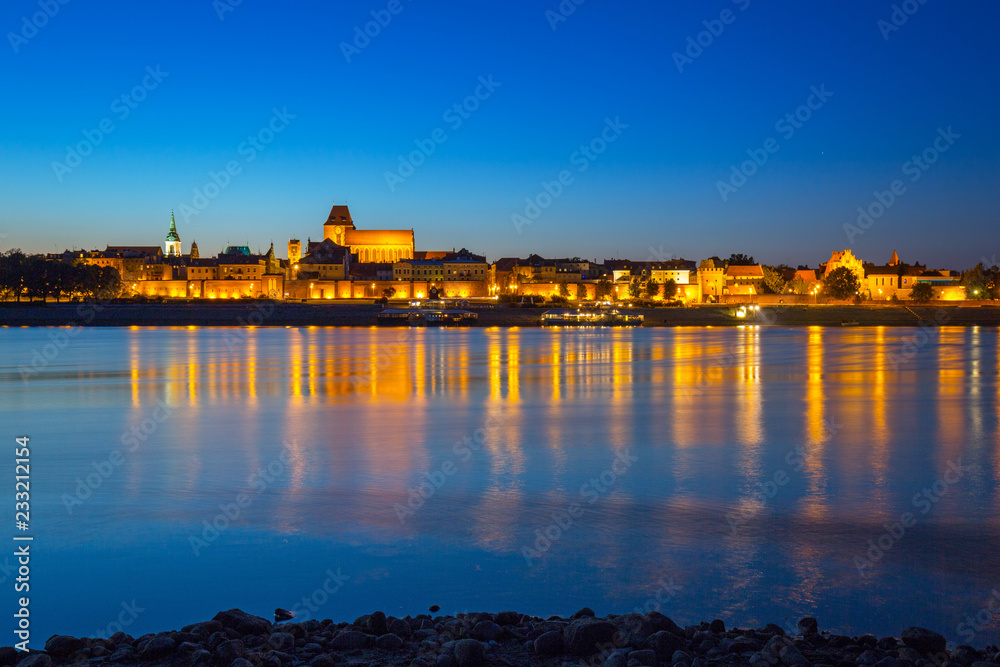 Old town of Torun at night reflected in Vistula river, Poland