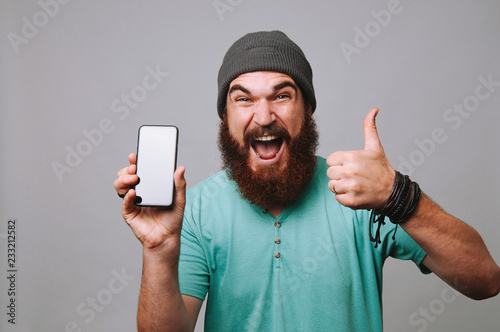 Excited man holding phone and showing thumbs up photo