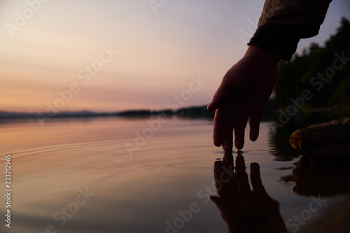 Human hand touching the fresh water from lake. Close-up. Lifestyles concept.