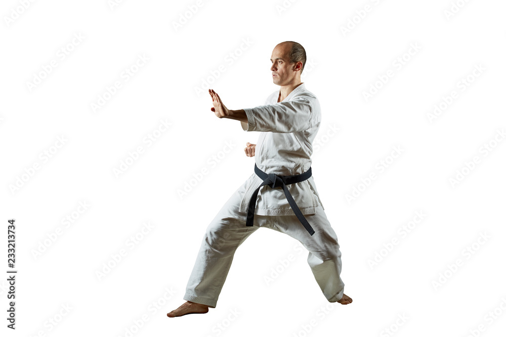 Athlete trains karate exercises on white isolated background
