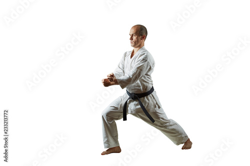 On white isolated background athlete performs formal karate exercises.