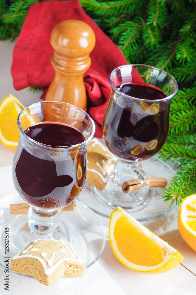 Mulled wine with cinnamon sticks in glass and cookies on wooden table with christmas tree branch on background Mulled wine with cinnamon sticks in glass and cookies on wooden table with christmas tree branch on background