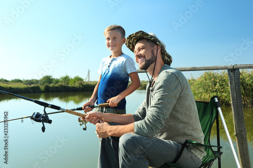 Father and son fishing together on sunny day © New Africa