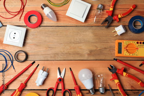 Flat lay composition with electrician's tools and space for text on wooden background