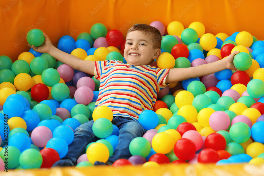 Cute little child playing in ball pit at indoor amusement park Cute little child playing in ball pit at indoor amusement park