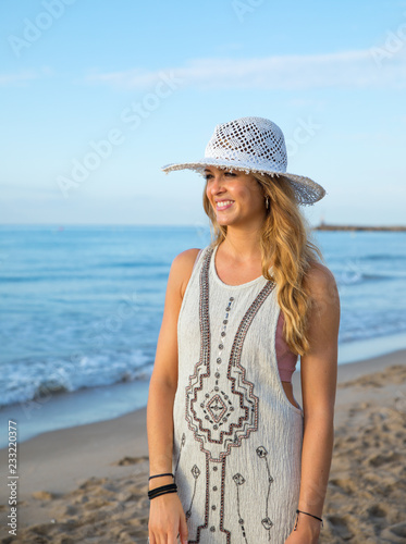 blonde young girl on the beach with dress and hat