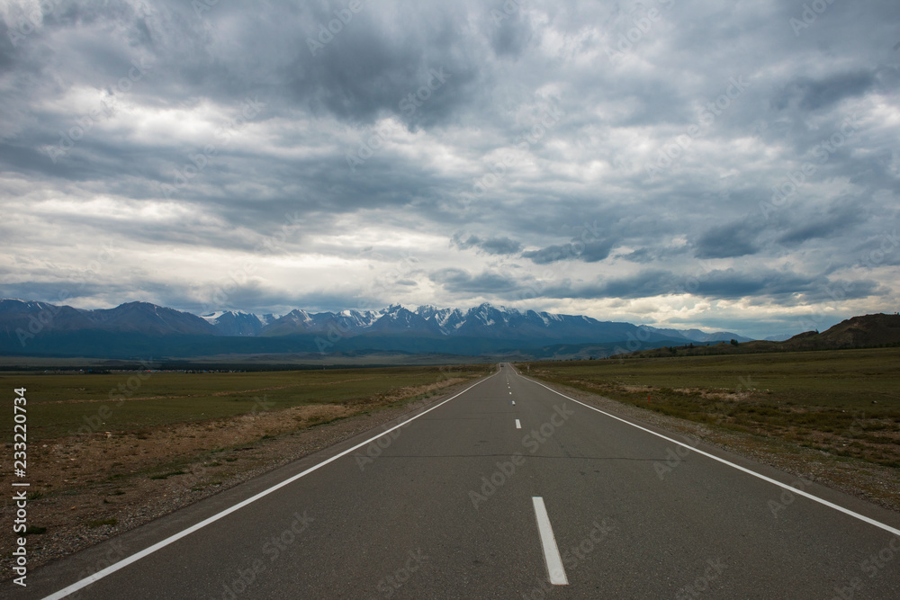 Empty route in Altai mountains on snowly peaks background