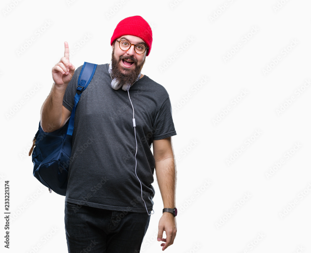 Fototapeta premium Young hipster man wearing red wool cap and backpack over isolated background pointing finger up with successful idea. Exited and happy. Number one.