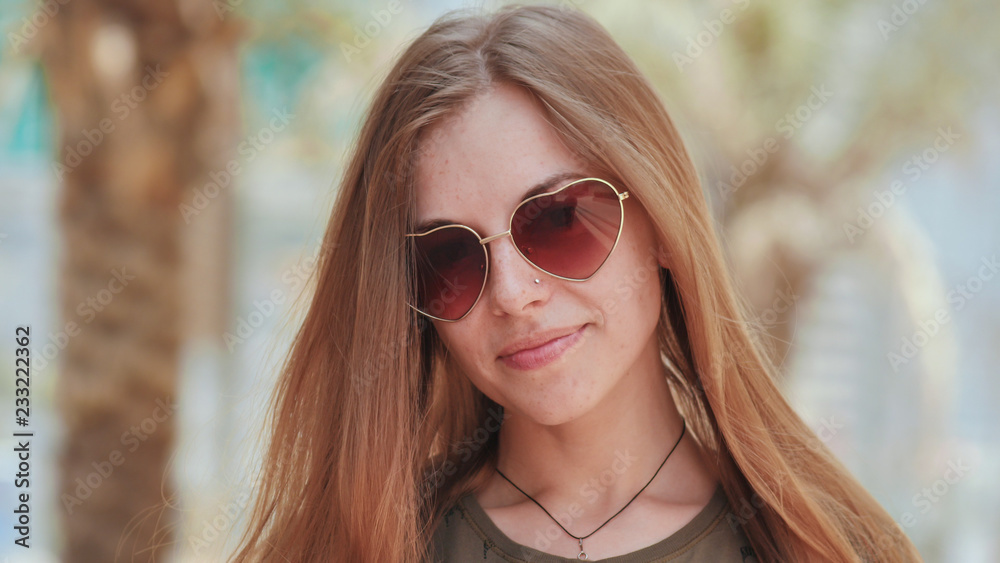 Girl in sunglasses on the background of Dubai streets and palms trees. Face close-up.