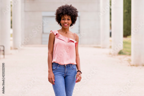 Happy young beautiful afro american woman smiling. White columns background. Spring or summer season. Casual clothing outdoors