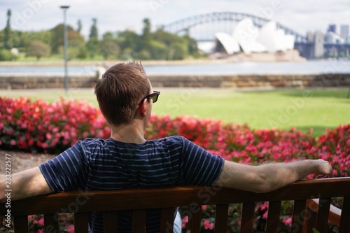 Man from behind on park bench in Sidney, Australia looking at opera house and harbour bridge in summer © mbrachi