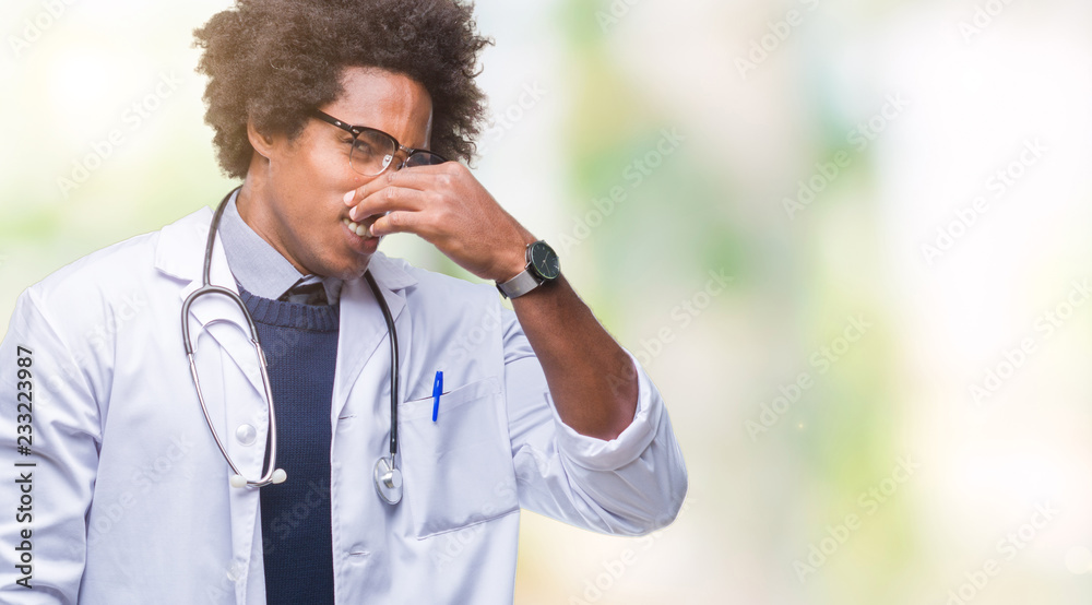 Afro american doctor man over isolated background smelling something stinky and disgusting, intolerable smell, holding breath with fingers on nose. Bad smells concept. Afro american doctor man over isolated background smelling something stinky and disgusting, intolerable smell, holding breath with fingers on nose. Bad smells concept.