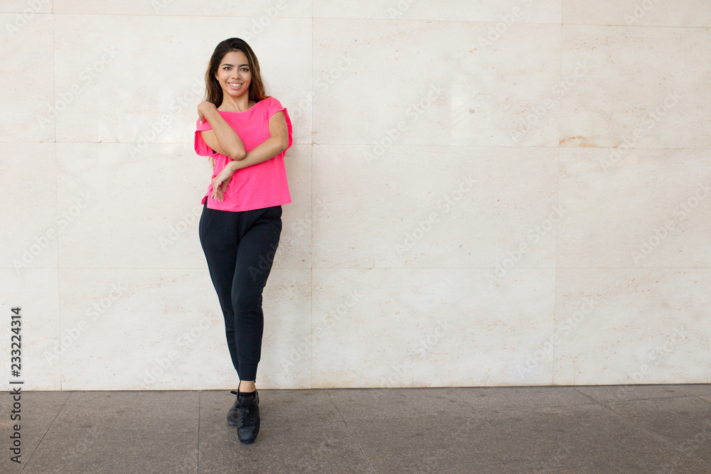 Joyful street dancer warming up. Beautiful mix raced woman in fitness apparel stretching arms. Outdoor training concept Joyful street dancer warming up. Beautiful mix raced woman in fitness apparel stretching arms. Outdoor training concept