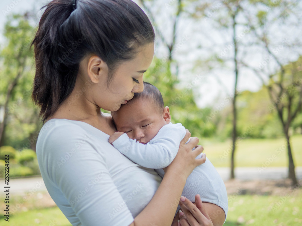 Happy family, Pretty woman holding a newborn baby in her arms on nature park in summer Happy family, Pretty woman holding a newborn baby in her arms on nature park in summer