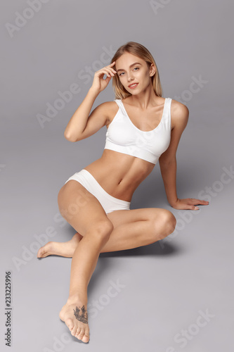 Perfect slim toned young body of the girl or fit woman at studio. The fitness, diet, sports, plastic surgery and aesthetic cosmetology concept.