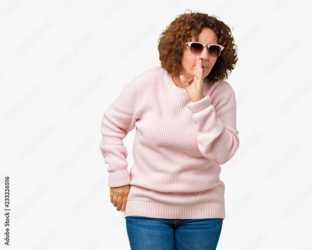 Beautiful middle ager senior woman wearing pink sweater and sunglasses over isolated background hand on mouth telling secret rumor, whispering malicious talk conversation Beautiful middle ager senior woman wearing pink sweater and sunglasses over isolated background hand on mouth telling secret rumor, whispering malicious talk conversation