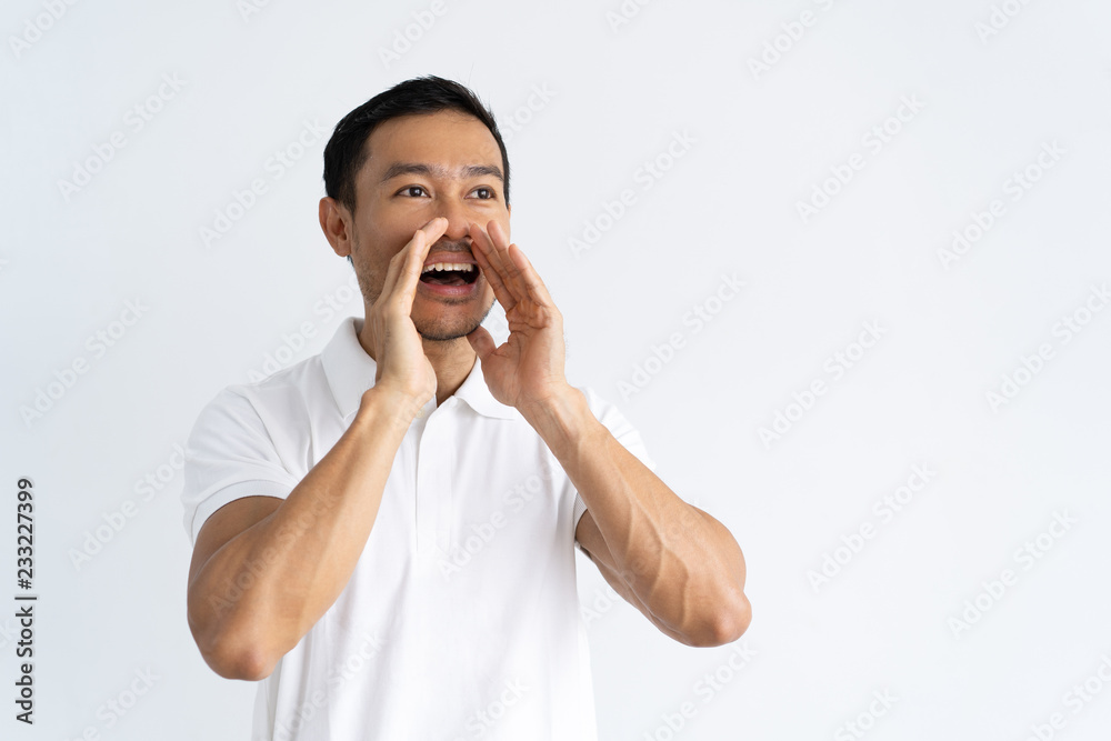 Joyful guy announcing great news. Positive young mix raced man dressed in white shouting loud with hands at mouth. Announcement concept Joyful guy announcing great news. Positive young mix raced man dressed in white shouting loud with hands at mouth. Announcement concept