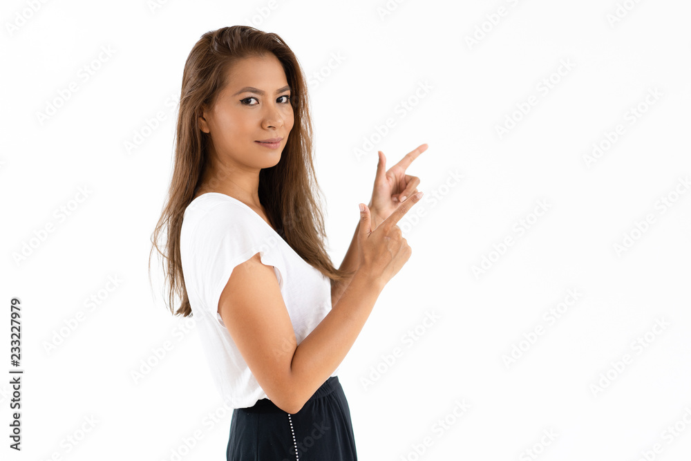 Smiling Latin girl sharing retail special offers. Positive young woman pointing index fingers away and looking at camera. Promotion concept Smiling Latin girl sharing retail special offers. Positive young woman pointing index fingers away and looking at camera. Promotion concept