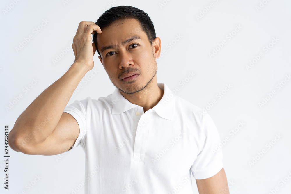 Thoughtful focused guy making serious decision. Handsome young man scratching head and looking at camera with pensive face. Thinking concept Thoughtful focused guy making serious decision. Handsome young man scratching head and looking at camera with pensive face. Thinking concept