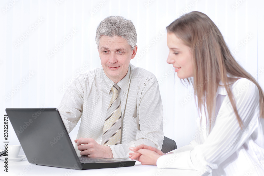 two members of the company sitting behind a Desk two members of the company sitting behind a Desk