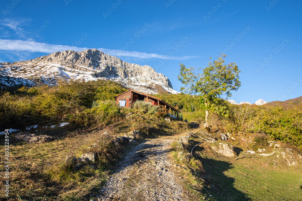 View of the mountain from the valley during sunset in the National Park of Picos de Europa in Sajambre, Leon (Spain). You see a red house in the valley View of the mountain from the valley during sunset in the National Park of Picos de Europa in Sajambre, Leon (Spain). You see a red house in the valley