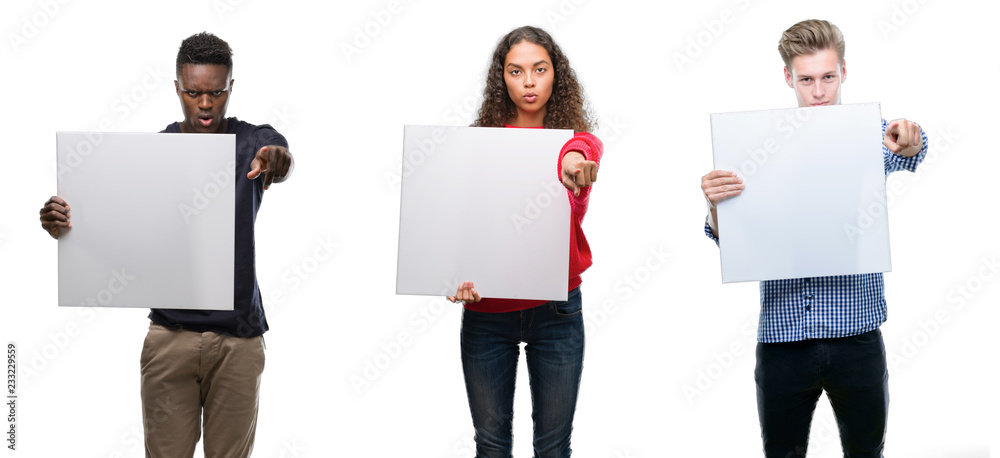 Composition of young people holding blank banner over isolated background pointing with finger to the camera and to you, hand sign, positive and confident gesture from the front Composition of young people holding blank banner over isolated background pointing with finger to the camera and to you, hand sign, positive and confident gesture from the front