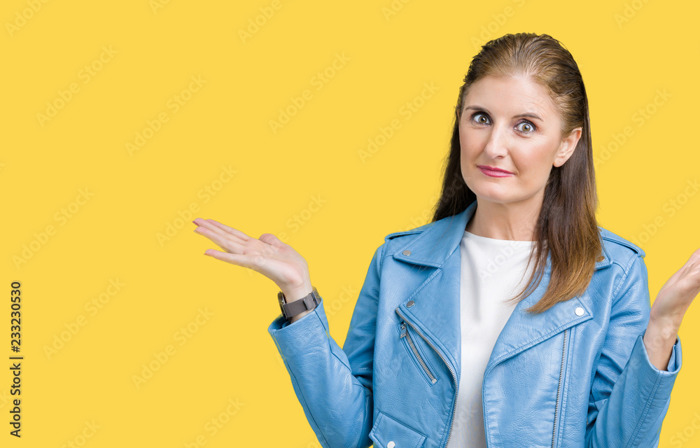 Beautiful middle age mature woman wearing fashion leather jacket over isolated background clueless and confused expression with arms and hands raised. Doubt concept. Beautiful middle age mature woman wearing fashion leather jacket over isolated background clueless and confused expression with arms and hands raised. Doubt concept.