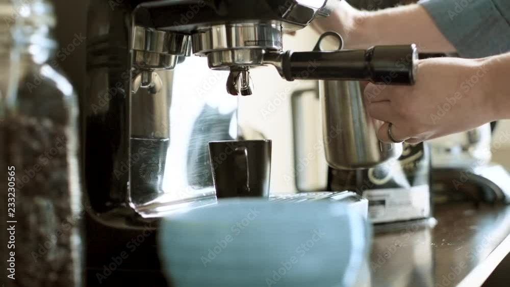 Hot, Fresh, Steamy Coffee being Pulled into a Shot Glass on a Espresso Machine with Barista Steaming Milk in Background. Then Cleaning Steamer Spout with a Cloth in Super Slow Motion Hot, Fresh, Steamy Coffee being Pulled into a Shot Glass on a Espresso Machine with Barista Steaming Milk in Background. Then Cleaning Steamer Spout with a Cloth in Super Slow Motion