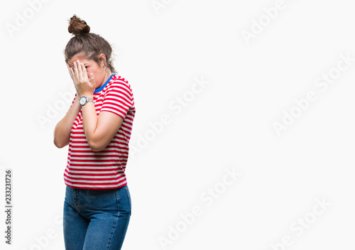 Beautiful brunette curly hair young girl wearing casual look over isolated background with sad expression covering face with hands while crying. Depression concept. © Krakenimages.com
