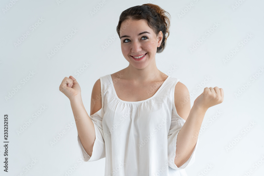 Happy lovely woman pumping fists and celebrating success. Young lady looking away. Achievement concept. Isolated front view on white background. Happy lovely woman pumping fists and celebrating success. Young lady looking away. Achievement concept. Isolated front view on white background.