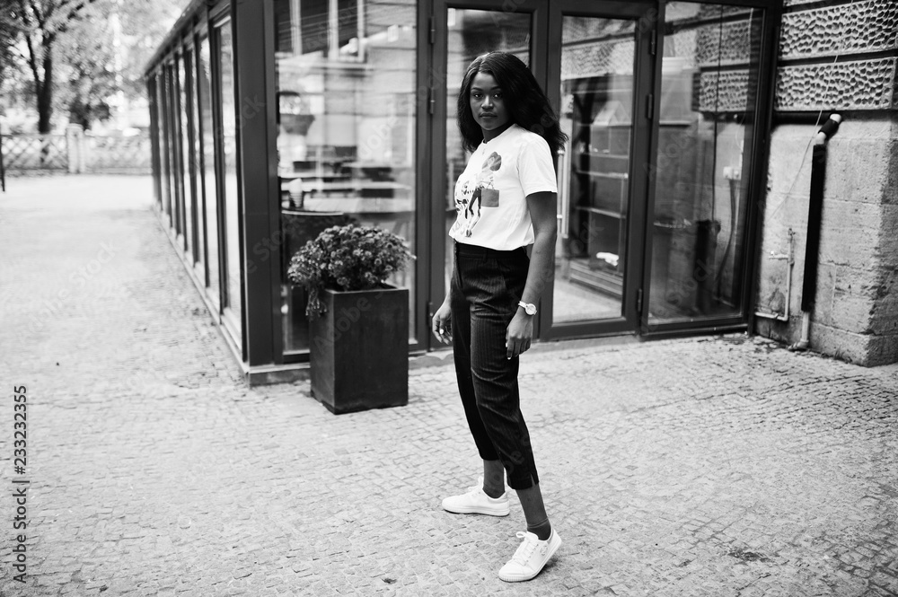 Φωτογραφία Stylish african american woman in printed t-shirt posed outdoor against window