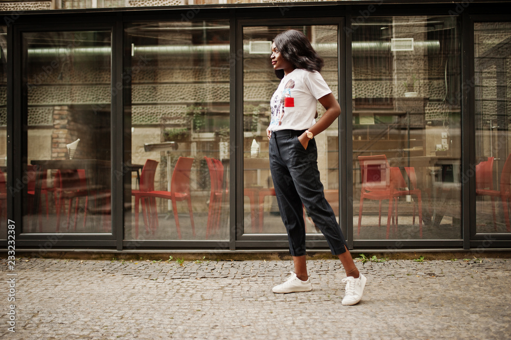 Φωτογραφία Stylish african american woman in printed t-shirt posed outdoor against window