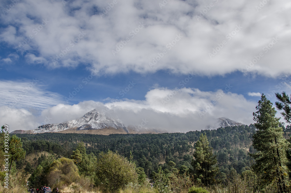 Fototapeta premium montaña nevada cielo azul, bosque de coníferas, nubes y volcanes, nevado de toluca mexico